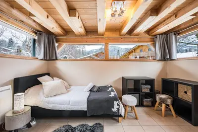 a bedroom with a bed and a wooden ceiling at Chalet Etelley - Jacuzzi Privé in Samoëns