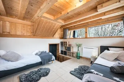 two beds in a room with wooden ceilings at Chalet Etelley - Jacuzzi Privé in Samoëns