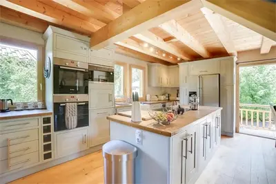 a large kitchen with white cabinets and a wooden ceiling at Chalet Etelley - Jacuzzi Privé in Samoëns