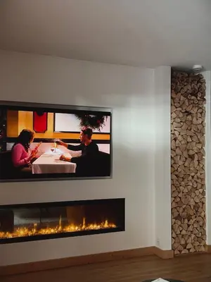 a tv hanging on a wall with a fireplace at Soleil in Chamonix-Mont-Blanc