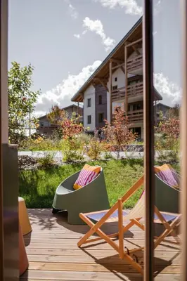 two chairs and a table on a deck with a building at Veriaz - Appart 1 CH Cocon Design Confort in Megève