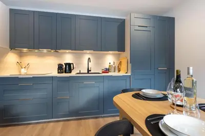 a kitchen with blue cabinets and a wooden table at Babotches - Chalet 110m2 Moderne Familial 7 pax in Chamonix-Mont-Blanc