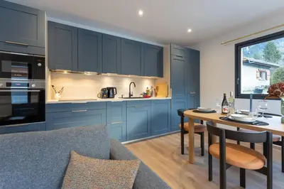 a kitchen with blue cabinets and a table with chairs at Babotches - Chalet 110m2 Moderne Familial 7 pax in Chamonix-Mont-Blanc