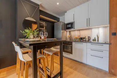 a kitchen with white cabinets and a table with chairs at Straton - Cosy 1 CH Modern Hypercentre Transport 150m in Chamonix-Mont-Blanc
