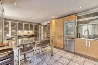 a kitchen with wooden cabinets and a counter with chairs at Clairtemps- Charmant Chalet 168 m2 6 Pax Familial Vue in Les Houches