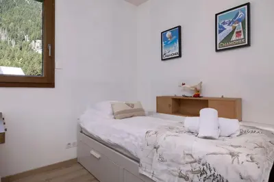 a bedroom with a bed with white sheets and a window at Les Iles - Chalet 165m2 Vue Mont Familial 10 pax in Chamonix-Mont-Blanc