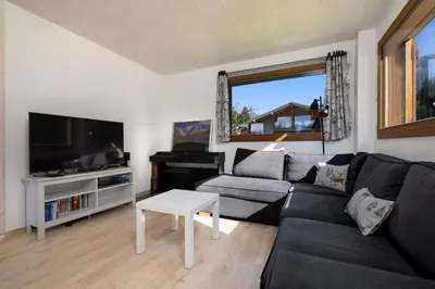a living room with a black couch and a tv at Les Iles - Chalet 165m2 Vue Mont Familial 10 pax in Chamonix-Mont-Blanc