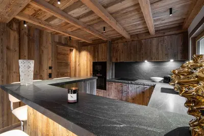 a kitchen with a black counter top and wooden walls at Superb Chalet Isatis-renovated in Megeve in Megève