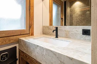 a bathroom with a white marble sink with a faucet at Superb Chalet Isatis-renovated in Megeve in Megève