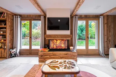 a living room with a fireplace and a tv at Superb Chalet Isatis-renovated in Megeve in Megève