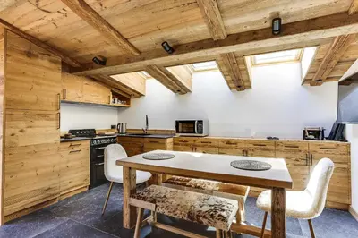 a kitchen with wooden walls and a table and chairs at Cozy 2BDR-5P apartment near the ski slopes in Megève