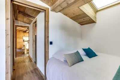 a bedroom with a white bed and wooden ceilings at Cozy 2BDR-5P apartment near the ski slopes in Megève