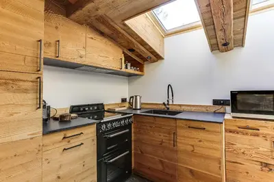 a kitchen with wooden cabinets and a black stove top oven at Cozy 2BDR-5P apartment near the ski slopes in Megève
