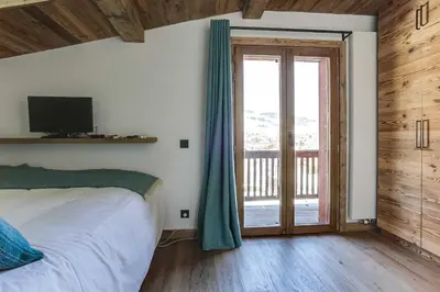 a bedroom with a bed and a sliding glass door at Cozy 2BDR-5P apartment near the ski slopes in Megève