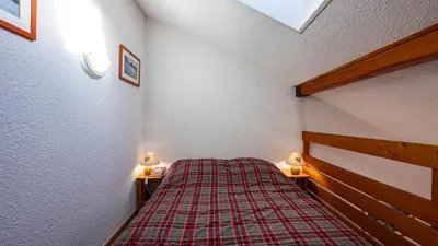 a bedroom with a bed with a plaid blanket at Grand Morillon N404 2P6 Mezzanine in Morillon