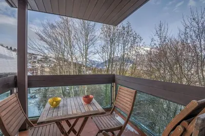 a deck with two chairs and a table on a balcony at Appartement L'Écrin du Mont d'Arbois - Welkeys in Saint-Gervais-les-Bains