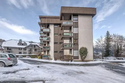 a building with a car parked in a parking lot at Appartement L'Écrin du Mont d'Arbois - Welkeys in Saint-Gervais-les-Bains