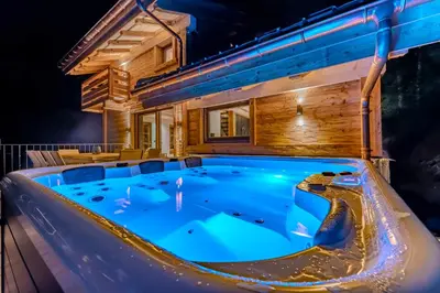 a hot tub on a deck at night at Luxurious Chalet with Sauna & Jacuzzi in Megeve with Parking in Megève