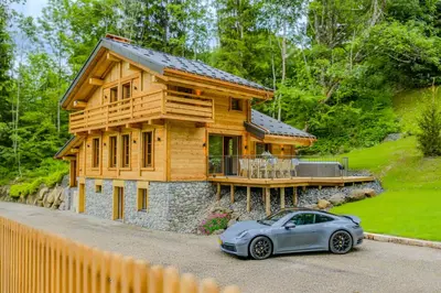 a car parked in front of a wooden house at Luxurious Chalet with Sauna & Jacuzzi in Megeve with Parking in Megève