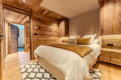 a bedroom with a bed and a wooden wall at Luxurious Chalet with Sauna & Jacuzzi in Megeve with Parking in Megève