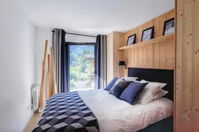 a bedroom with a large bed with a large window at Beautiful apartment in 5 stars residence with pool in Chamonix-Mont-Blanc