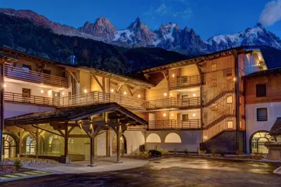 a large building with mountains in the background at Beautiful apartment in 5 stars residence with pool in Chamonix-Mont-Blanc
