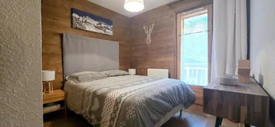 a bedroom with a bed and a window at LES BEULETTES b in Samoëns