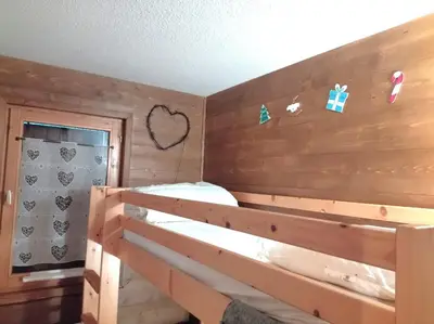a bedroom with wooden walls and a bunk bed at LES BEULETTES b in Samoëns