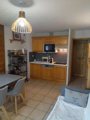a kitchen with wooden cabinets and a table and a microwave at LES BEULETTES b in Samoëns
