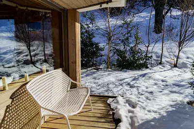 a wicker chair sitting on a porch in the snow at Appartement Le Pacha - Proche Centre Ville in Megève