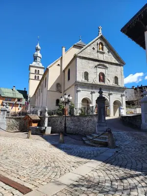 an old building with a clock tower and a church at Appartement Le Pacha - Proche Centre Ville in Megève