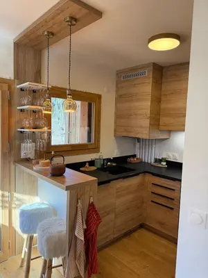 a kitchen with wooden cabinets and a counter with stools at Contamines Montjoie appartement 2 chambres et cabine in Les Contamines-Montjoie