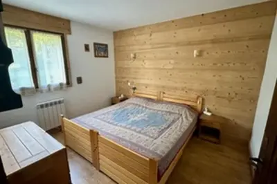 a bedroom with a bed with a wooden wall at Stay at the heart of the slopes in Megève! in Megève