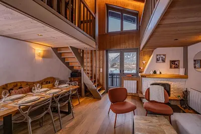 a dining room with a table and chairs and a staircase at Balcons de Champraz- Spectacular Mont Blanc and Lake Views in Chamonix-Mont-Blanc