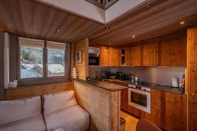 a living room with a couch and a kitchen at Balcons de Champraz- Spectacular Mont Blanc and Lake Views in Chamonix-Mont-Blanc