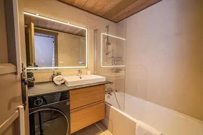 a bathroom with a sink and a washing machine at Balcons de Champraz- Spectacular Mont Blanc and Lake Views in Chamonix-Mont-Blanc