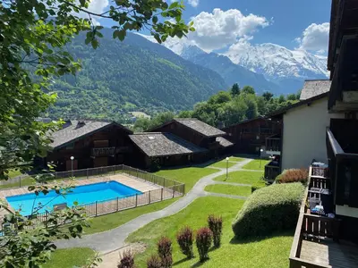 a house with a pool and mountains in the background at Duplex Saint Gervais - Ski, piscine & vue in Saint-Gervais-les-Bains