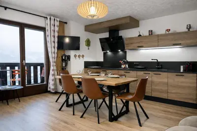 a kitchen with a wooden table and chairs in a room at Duplex Saint Gervais - Ski, piscine & vue in Saint-Gervais-les-Bains