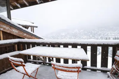 a table and chairs on a balcony covered in snow at Duplex Saint Gervais - Ski, piscine & vue in Saint-Gervais-les-Bains
