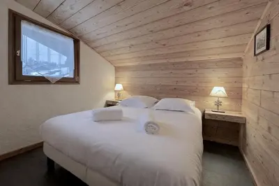 a bedroom with a large white bed with a window at Duplex Saint Gervais - Ski, piscine & vue in Saint-Gervais-les-Bains