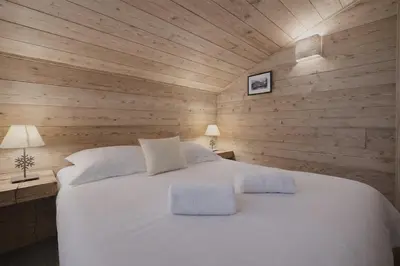 a bedroom with a white bed in a wooden wall at Duplex Saint Gervais - Ski, piscine & vue in Saint-Gervais-les-Bains