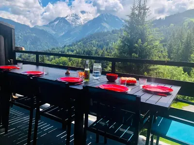 a table on a balcony with a view of mountains at Odyssée des Cimes in Saint-Gervais-les-Bains