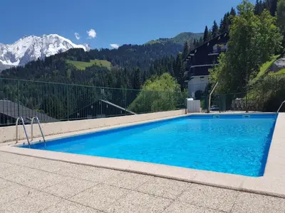 a swimming pool with mountains in the background at Odyssée des Cimes in Saint-Gervais-les-Bains