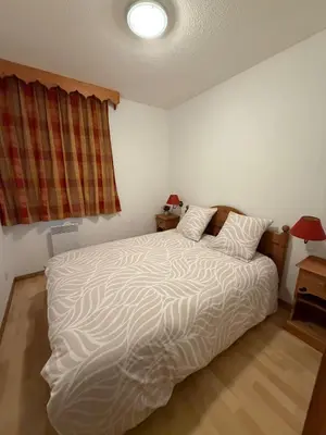 a bedroom with a large white bed with two pillows at Sympathique appartement à Samoëns in Samoëns