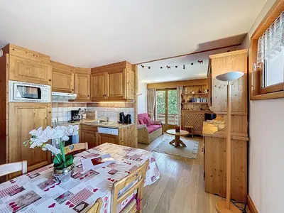 a kitchen with wooden cabinets and a table with flowers on it at Appartement 3 Pièces avec Parking et Vue Mont Blanc - FR-1-560-174 in Combloux