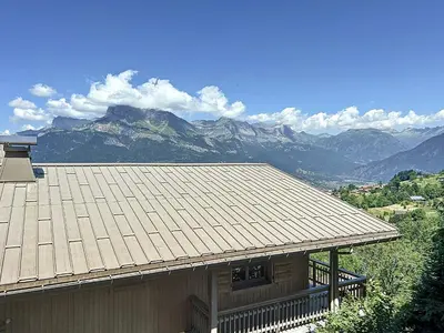 a house with a roof with mountains in the background at Appartement 3 Pièces avec Parking et Vue Mont Blanc - FR-1-560-174 in Combloux