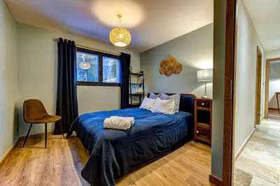 a bedroom with a blue bed and a chair at Beautiful new flat by the forest in Chamonix-Mont-Blanc