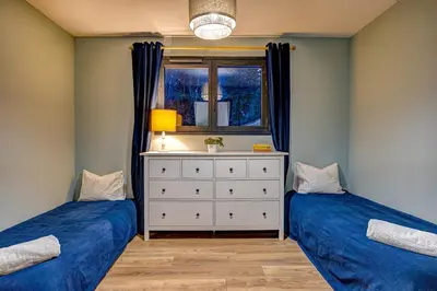 two beds in a room with a dresser and a window at Beautiful new flat by the forest in Chamonix-Mont-Blanc