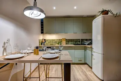 a kitchen with a table with wine glasses and a refrigerator at Beautiful new flat by the forest in Chamonix-Mont-Blanc