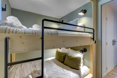 two bunk beds in a room with white sheets at Ancelles - Cocon 1CH Balcon Parking HomeCine CentrePraz in Chamonix-Mont-Blanc